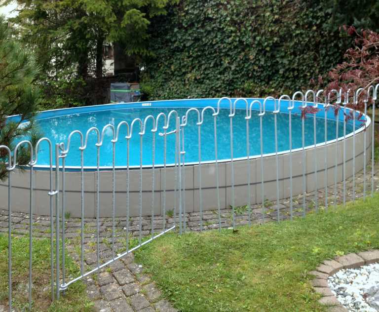 Ein Schutz Zaun mit Türchen vor einem Schwimmbad im Garten