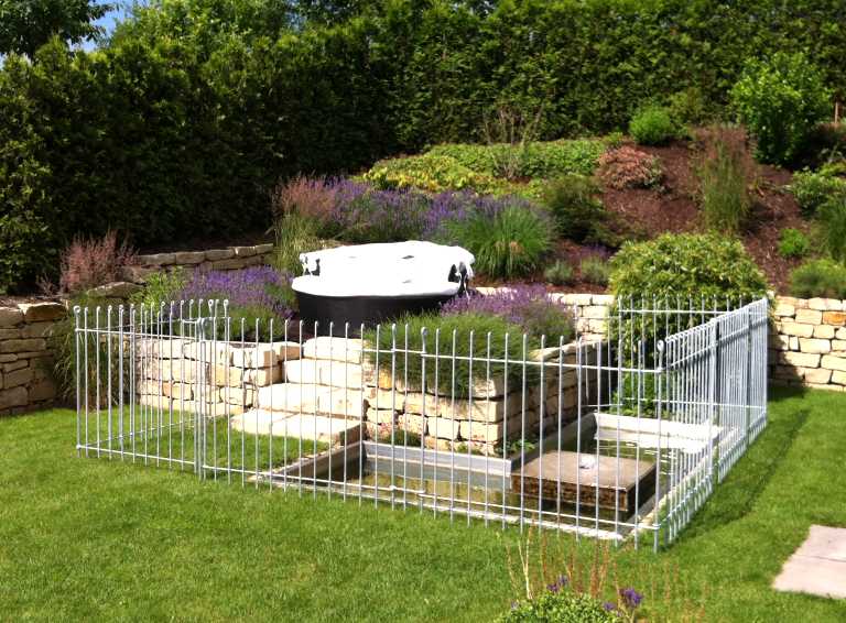 Der Garten Zaun mit Gartentürchen schützt ein Wasserbecken kindersicher 